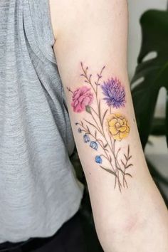 a woman with a tattoo on her arm has flowers painted on the back of her arm