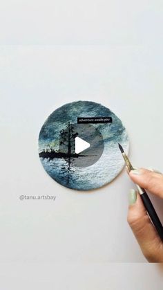 someone holding a pen and drawing on a circular sticker