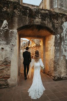 a bride and groom walking through an old building