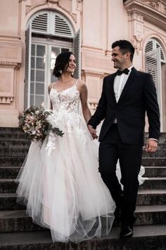 a bride and groom are walking down the stairs together in front of an old building