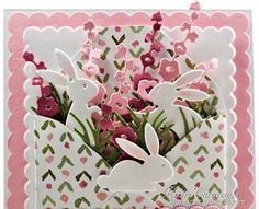 an easter card with pink flowers and white rabbits