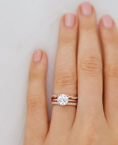 a woman's hand with two wedding rings on her left and the other hand holding an engagement ring