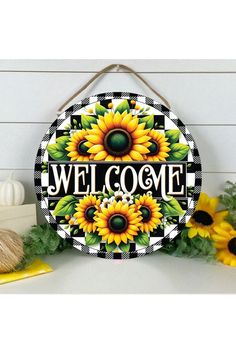 a welcome sign with sunflowers is hanging on the wall next to some flowers