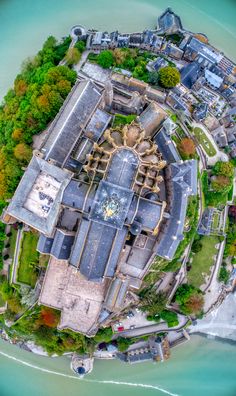 an aerial view of a large building in the middle of some water and trees around it