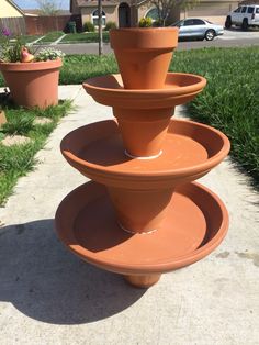 three clay pots stacked on top of each other in the middle of a sidewalk next to grass