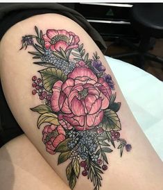 a woman's thigh with pink flowers and leaves on her leg, in front of a table