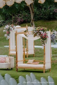 an outdoor ceremony setup with white chairs and pink flowers on the back drop cloths