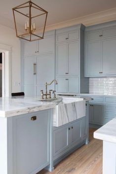 a large kitchen with marble counter tops and blue cabinets, an island in the middle