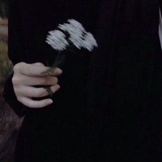 a person holding a flower in their hand and wearing a black shirt with white writing on it