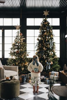 a woman standing in front of a christmas tree