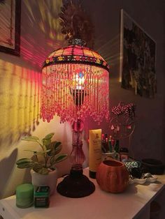 a pink lamp sitting on top of a table next to a pot filled with plants