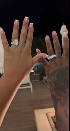 two women's hands with wedding rings on their fingers, one holding the other