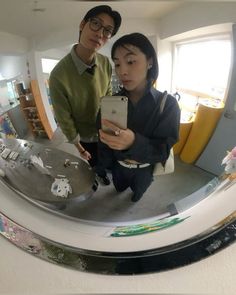 a man and woman taking a selfie in front of a mirror with an iphone