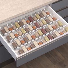 an open drawer with spices and seasonings in it on a wooden floor next to a marble counter top