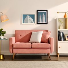 a living room with a pink couch and two framed pictures on the wall above it