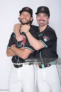 two baseball players are hugging each other and posing for a photo with their arms around each other