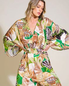 a woman wearing a green and brown leaf print robe with her hands on her hips