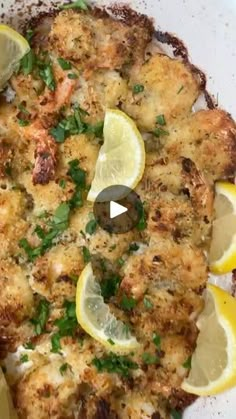 a white plate topped with food covered in lemons and parsley next to sliced up lemon wedges