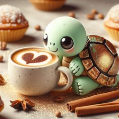 a little turtle sitting on top of a cup of coffee next to some cinnamons