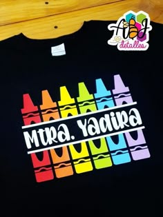 a black shirt with colorful crayons on it that says mura yaquipa