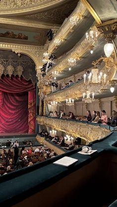 an auditorium filled with lots of people and chandeliers