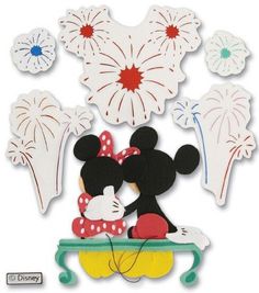 mickey and minnie mouse cut outs with fireworks in the sky behind them on a table