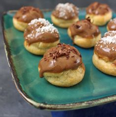 chocolate frosted donuts are on a green platter with powdered sugar and sprinkles