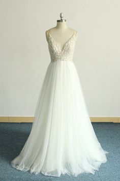 a white wedding dress on a mannequin in front of a blue carpeted floor