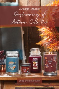 yankee candles are displayed on a table with autumn decorations