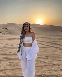 a woman standing in the desert at sunset