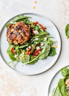 two white plates topped with spinach and meat patties