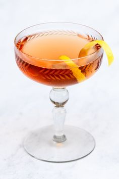 a glass filled with a drink and garnished with an orange peel on the rim