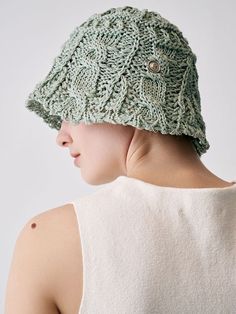 a woman wearing a green knitted hat with buttons on the front and back of her head