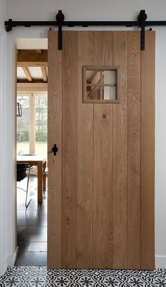 an open wooden door in a room with black and white flooring