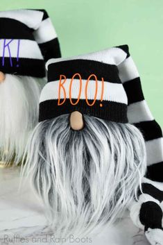 two halloween gnomes wearing black and white striped hats with boo written on the front