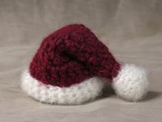 a red and white knitted santa hat laying on top of a tablecloth covered surface