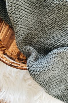 a basket with a blanket on top of it next to a white fluffy chair cushion