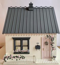 a white house with a pink door and window on the outside, sitting on a table next to a potted plant