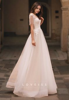 a woman in a white wedding dress standing on a stone walkway with her hand on her hip