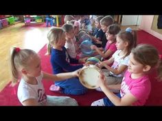 a group of children sitting on the floor playing with drums