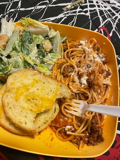 a yellow plate topped with spaghetti and salad