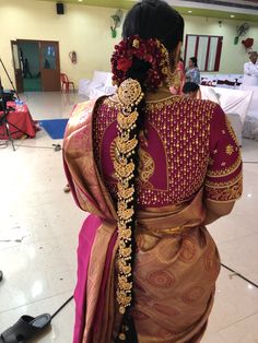 the back of a woman's sari with gold and red flowers in her hair