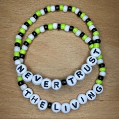 two bracelets that say never trust the living and one with green, white and black beads