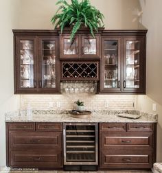 a kitchen with wooden cabinets and marble counter tops, wine glasses on the cabinet doors