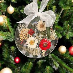 a glass ornament with flowers on it hanging from a christmas tree