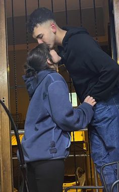 a man and woman kissing each other in front of an open door with bars behind them