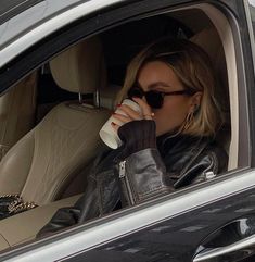 a woman sitting in the back seat of a car drinking out of a coffee cup