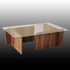 a glass and wood coffee table sitting on top of a black floor