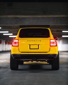 the back end of a yellow car in a parking garage