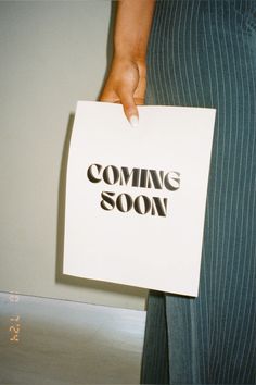 a person holding a paper with the words coming soon printed on it